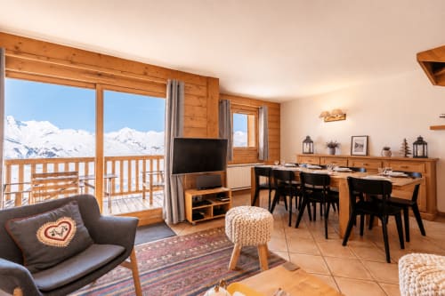 Luxury apartment living room with Mont-Blanc mountain view, wooden furnishings, dining area, and balcony at Arc 1800 ski