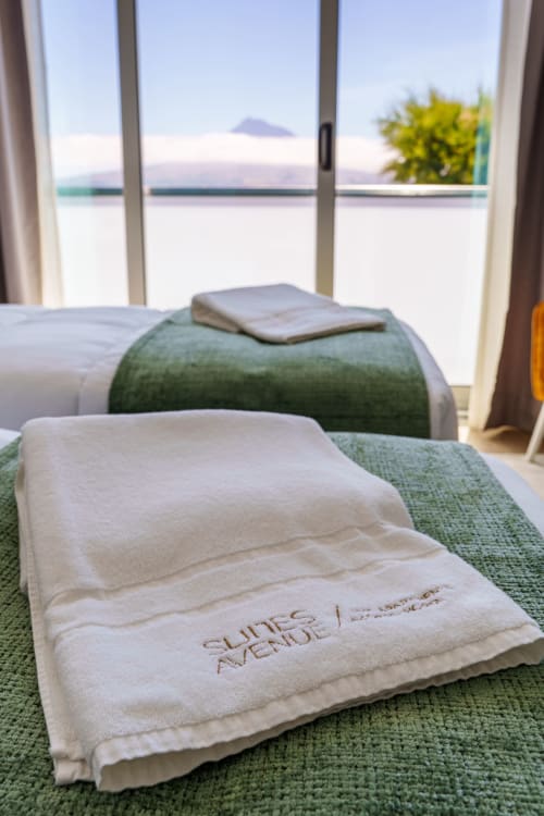 Luxury bedroom at Suites Avenue with ocean view of Faial island, folded towels on green bedding