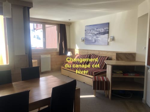 Séjour cosy aux Cristaux de La Plagne avec vue montagne, canapé rayé, table à manger et boiseries