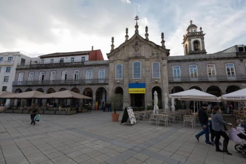 Igreja histórica de pedra com campanário na praça de Braga, esplanada ao ar livre, arquitetura colonial, Portugal