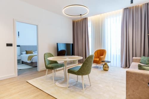 Área de estar da suíte moderna no Suites Avenue Lux Apartments em Horta com mesa de jantar, cadeiras verdes e vista para o quarto