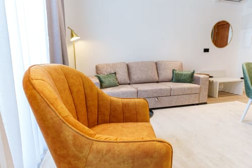 Modern living room at Suites Avenue Lux Apartments in Horta with orange leather chair and gray sofa