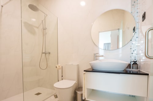 Modern bathroom at Suites Avenue Lux Apartments in Horta with walk-in shower, vessel sink, and round mirror