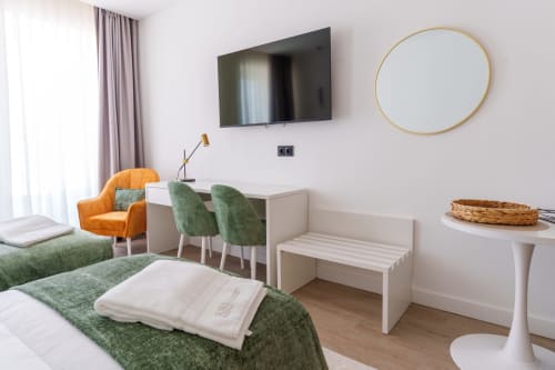 Modern hotel suite at Suites Avenue Lux Apartments in Horta with green upholstered furniture, workspace, TV, and elegant