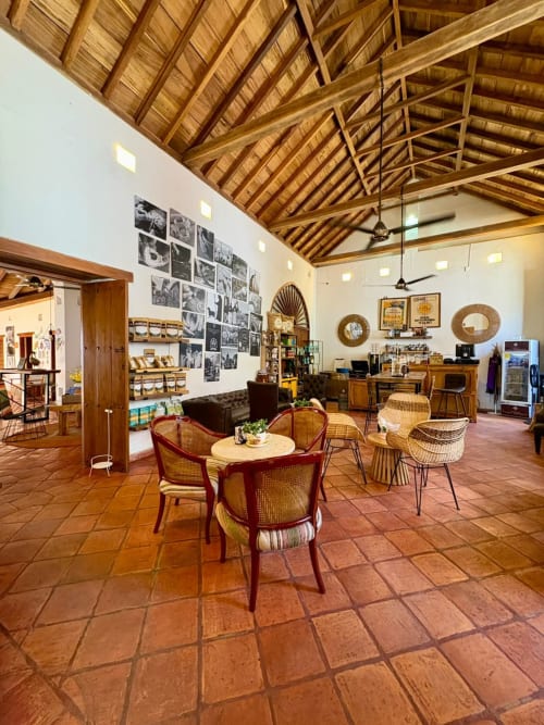 Salón colonial de Casa Gerar Filigrana en Mompox con vigas de madera, muebles vintage y fotografías en blanco y negro.