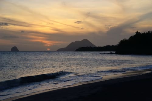 Vue de plage au coucher de soleil avec montagne   et rivage de sable  près du village du Diamant  Martinique