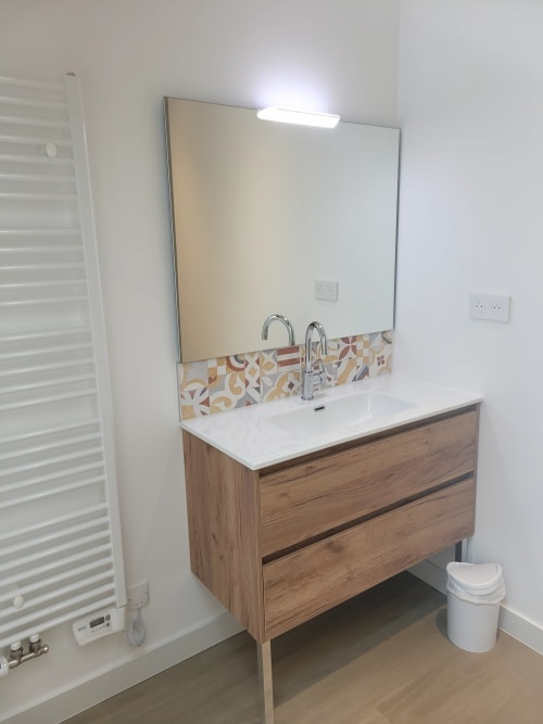 Salle de bain moderne avec meuble vasque en bois, plan de travail blanc et miroir aux Chambres d'hôtes Le Clos de la Touche à Cheillé