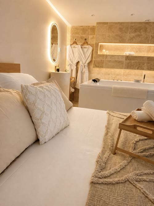 Suite luxueuse chambre-salle de bain à L'Escapade au Mans avec éclairage moderne, baignoire et élégante décoration crème
