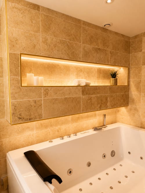 Baignoire spa luxueuse avec jets de balnéothérapie et étagère éclairée à l'hôtel L'Escapade au Mans