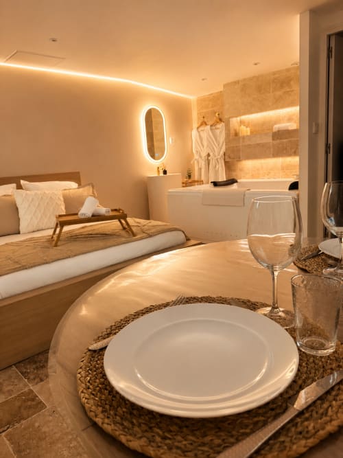 Suite chambre luxe à l'hôtel L'Escapade au Mans avec élégant coin repas et salle de bain moderne