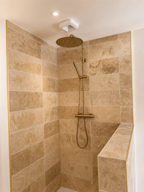 Douche à l'italienne moderne avec carrelage en travertin, pommeau de douche effet pluie et banc intégré à l'hôtel L'Escapade au Mans