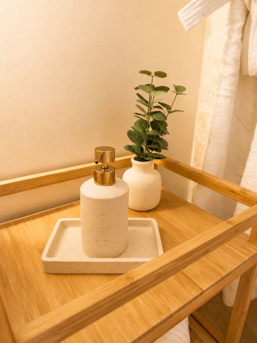Lavabo épuré à L'Escapade avec distributeur de savon, vase en céramique et plante verte sur plateau en bois