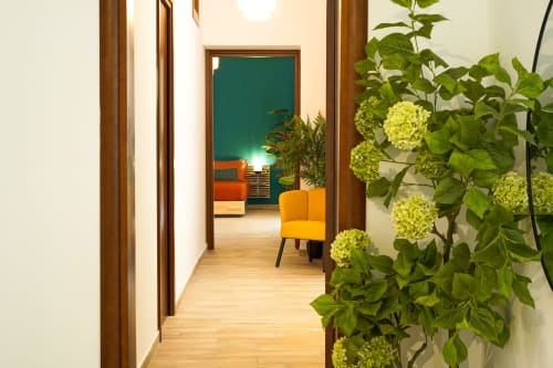Hallway at Calaba Decumani apartment in Naples with yellow flowers, wooden doors, and modern interior leading to guest room
