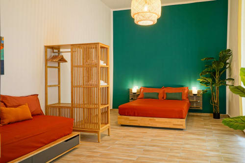 Calaba Decumani apartment in Naples featuring vibrant orange bed and sofa with teal accent wall