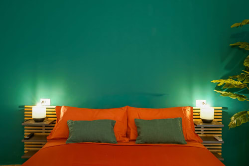 Modern bedroom at Calaba Napoli with orange bedding, green accents, wooden headboard, and ambient lighting
