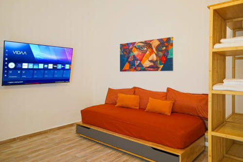 Modern Calaba apartment in Naples with red sofa, wall art, smart TV, and wooden shelving