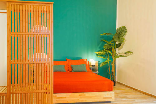 Calaba Decumani apartment in Naples featuring modern bedroom with bright orange bed, wooden partition, turquoise accent wall,
