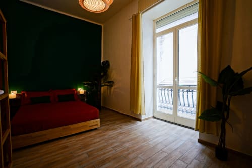 Calaba Decumani apartment in Naples with red bed, wooden floors, balcony doors, and city views