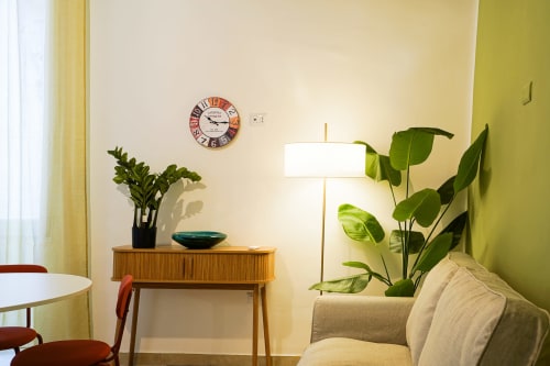 Calaba Decumani apartment in Naples with mid-century wooden console, potted plants, vintage clock, and modern lamp