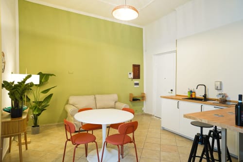 Calaba Decumani apartment in Naples with lime green accent wall, round dining table, cream sofa, and modern kitchenette
