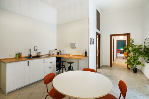 Bright modern kitchen and dining area at Calaba Decumani apartment in Naples, Italy with round table and orange chairs