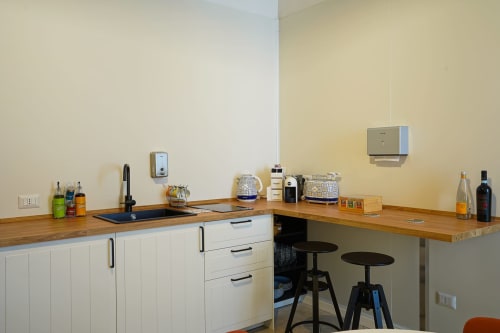 Modern kitchen in Calaba Decumani apartment, Naples with wooden counters, white cabinets, and bar seating overlooking city