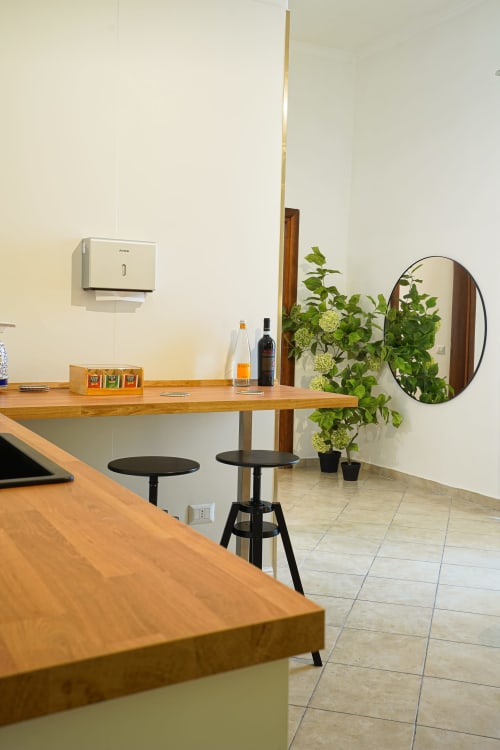 Modern Calaba Decumani apartment in Naples featuring wooden counters, bar seating, potted plants, and round mirror