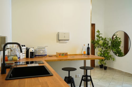 Modern kitchen area at Calaba Decumani apartment in Naples with wooden counter, bar stools, and city view
