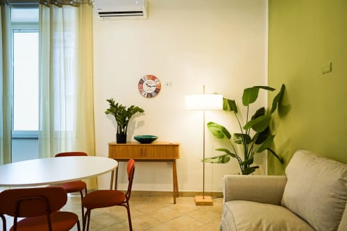 Calaba Decumani apartment in Naples features bright yellow walls, mid-century furniture, plants, and city views