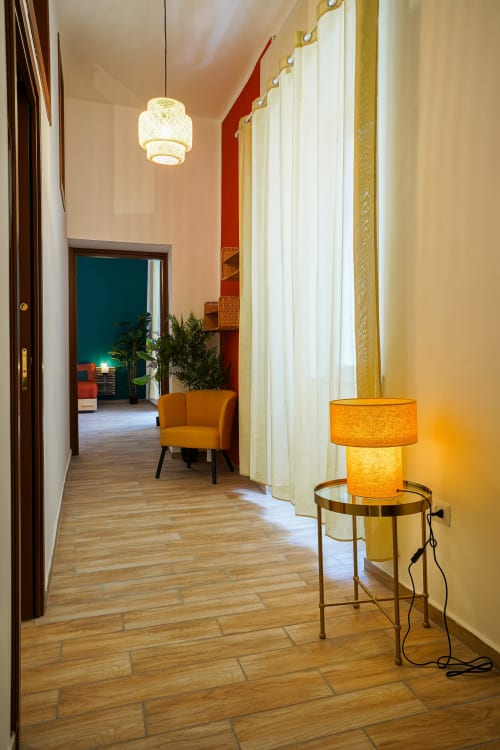 Elegant hallway at Calaba Decumani apartment in Naples with pendant lighting, orange chair, and warm ambient lighting