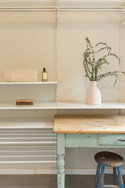 Minimalist bathroom vanity at Sea'Ya Villas with floating shelves, ceramic vase with greenery, and wooden desk in Cascais