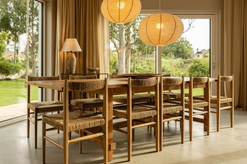 Modern dining room at Sea'Ya Villas with wooden chairs, woven seating, pendant lights, and garden views in Cascais