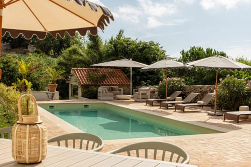 Sea'Ya Villas Cascais poolside with turquoise water, loungers, umbrellas, and Mediterranean gardens at sunset