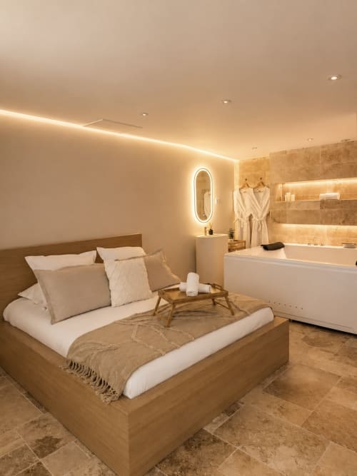 Chambre luxe avec salle de bains attenante à l'hôtel L'Escapade au Mans, avec lit en bois, éclairage chauffant et baignoire spa