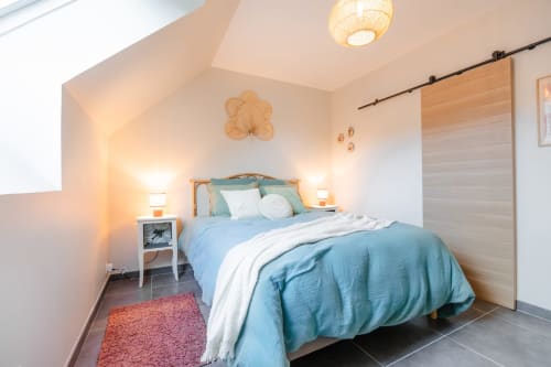 Chambre moderne au Hameau de Céline avec literie bleue, oreillers blancs, armoire en bois et vue sur le jardin