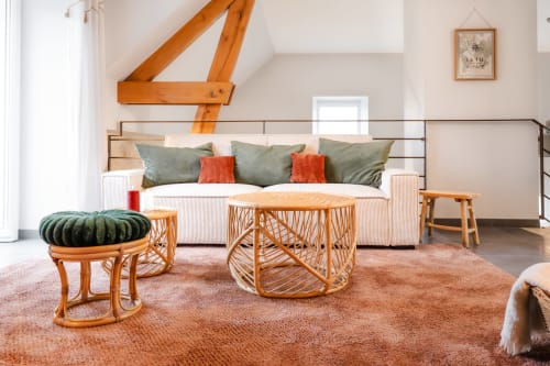 Salon de cottage moderne au Hameau de Céline avec mobilier en rotin, canapé et poutres apparentes