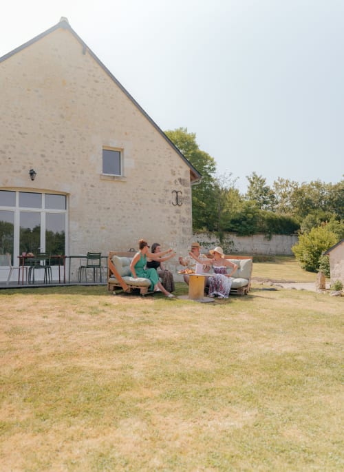 Des clients se détendent dans l'espace lounge du jardin de la maison d'hôtes Le Hameau de Céline à Landes-le-Gaulois, France