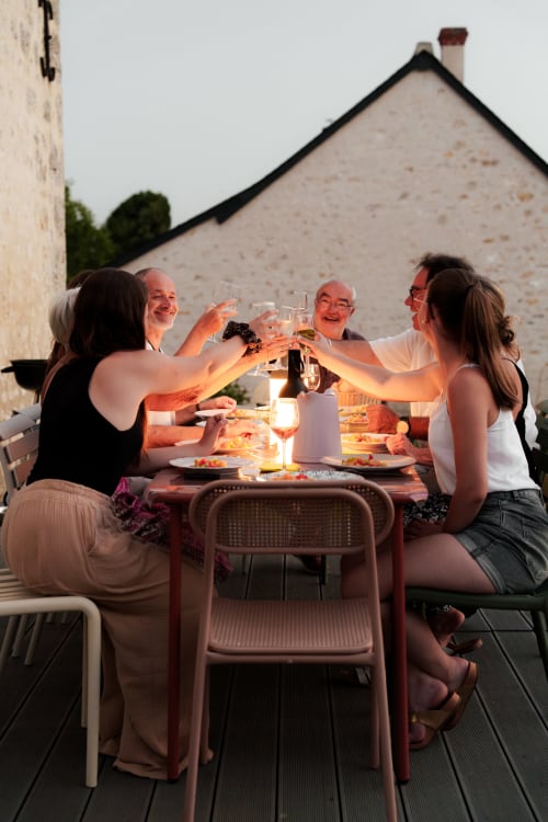 Groupe dégustant un dîner en soirée sur la terrasse du Hameau de Céline, Landes-le-Gaulois, vue sur la chaumière et ambiance festive