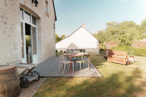 Terrasse en bois avec table à manger devant le cottage en pierre du Hameau de Céline, Landes-le-Gaulois, avec vue sur le jardin