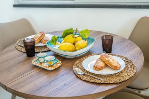 Tavolo da pranzo presso Origenes Rooms Procida con limoni freschi, pasticcini e servizio da tè nell'appartamento Ariè.
