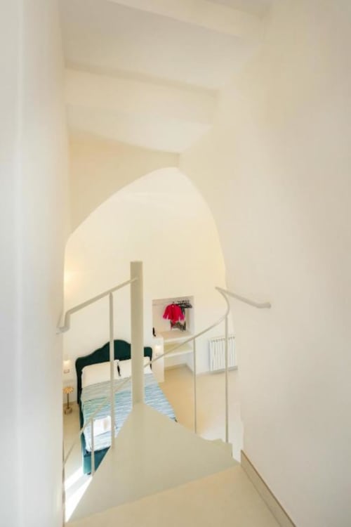 Camera moderna alle Origenes Rooms di Procida con porta ad arco, ringhiere in metallo e accesso alla vista sul mare