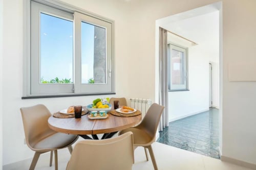 Elegante zona pranzo con tavolo rotondo in legno nella suite Ariè di Origenes Rooms a Procida, con vista mare e luminosa