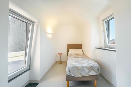 Camera luminosa presso Origenes Rooms a Procida con letto singolo, finestre e arredamento moderno minimalista