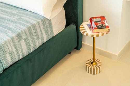 Letto verde con biancheria a righe e piccolo comodino con libri presso Origenes Rooms, Procida