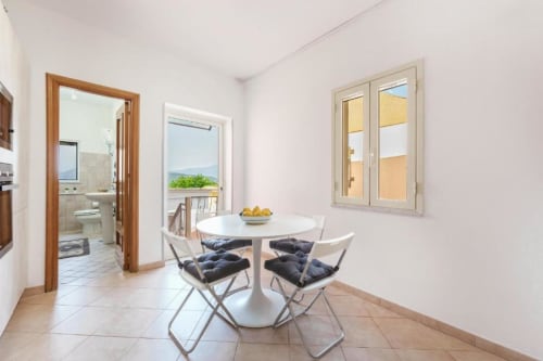 Luminosa zona pranzo con tavolo rotondo e sedie con vista oceano dalla terrazza dell'Apartment VILLALBE a Procida