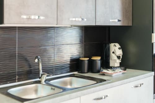 Moderna cucina in appartamento a Procida con lavello in acciaio inox, rivestimento nero testurizzato, caffettiera e mobiletto