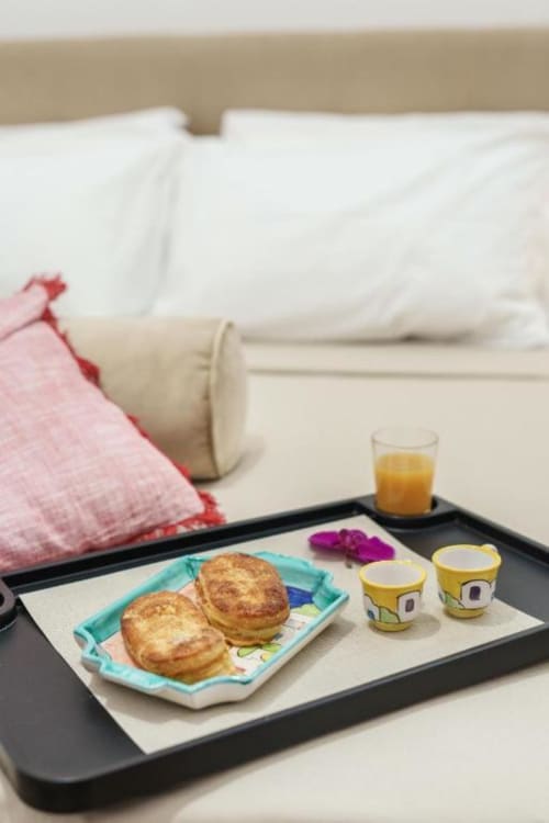 Vassoio colazione a letto presso Origenes Rooms Procida con pasticcini, yogurt, succo d'arancia e fiori
