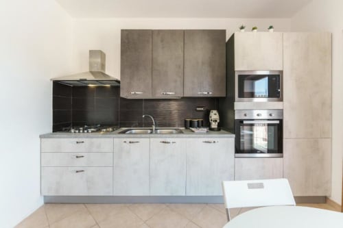 Cucina moderna nell'appartamento VILLALBE di Origenes Rooms, Procida con mobili chiari, schienale nero e acciaio inox