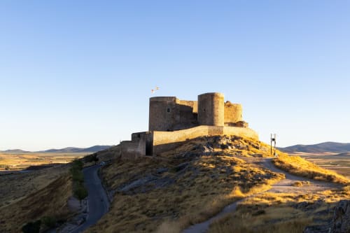 Castillo medieval fortaleza en la cima de la colina con vistas a las llanuras de Consuegra, bandera ondeando, cerca del Hostal San Poul
