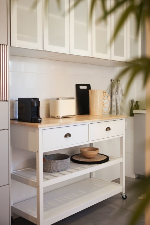 Modern kitchen cart with white drawers, wooden countertop, and decorative items at Sea'Ya Villas Cascais